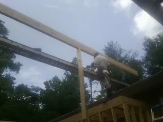 Carpenter setting a ridge beam over a new addition frame — Ice Dam Removal by Roofing Brothers in Whitesboro