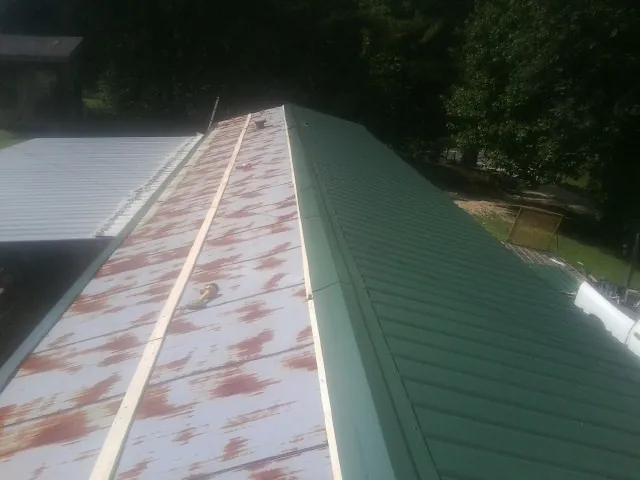 Old rusted panels beside newly installed green metal roofing — Wind Damage Roof Repair by Roofing Brothers in Whitesboro
