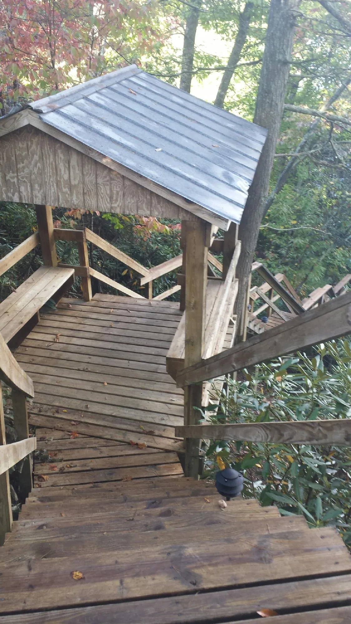 Metal roofed shelter over wooden steps on a wooded walkway — Skylight Repair & Installation work by our crew in Whitesboro
