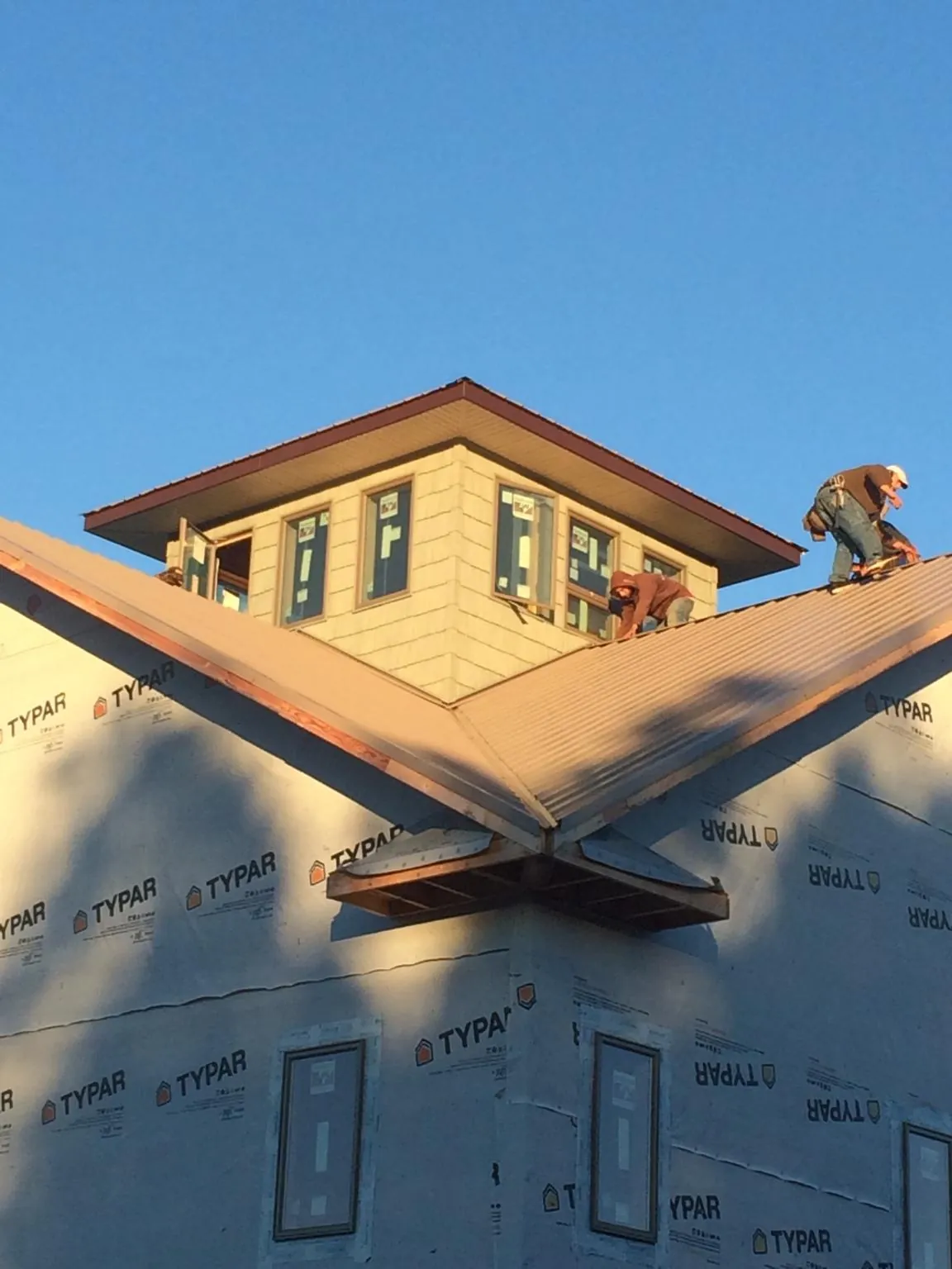 Roofers working around a rooftop cupola on a new metal roof at sunset — Roof Waterproofing in Whitesboro by Roofing Brothers